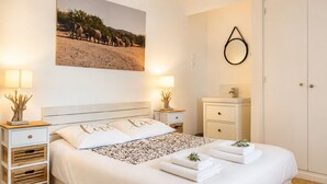 Un dormitorio ordenado con cama, mesitas de noche, tocador, espejo, un cuadro en la pared y un armario.
