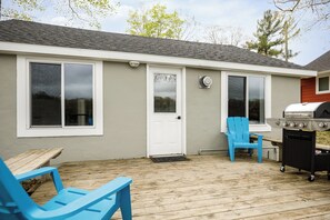 Une maison avec une terrasse, un barbecue et des chaises bleues.