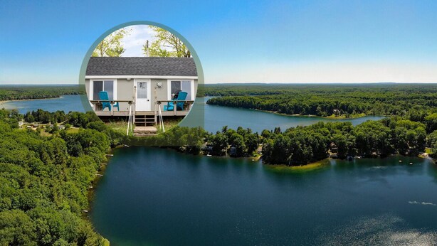 Una casa con balcón que da a un lago rodeado de bosque.