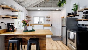 Una cocina moderna con encimeras de madera, una isla central con taburetes, un ventilador de techo y electrodomésticos integrados.