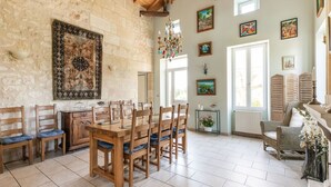 Un comedor con una mesa y sillas de madera, una araña y obras de arte en las paredes.