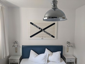 A bedroom with a bed, white curtains, a wall-mounted light fixture, a framed nautical-themed artwork, and a ceiling light. - Nice Holiday Home With Swimming Pool (Sellin)