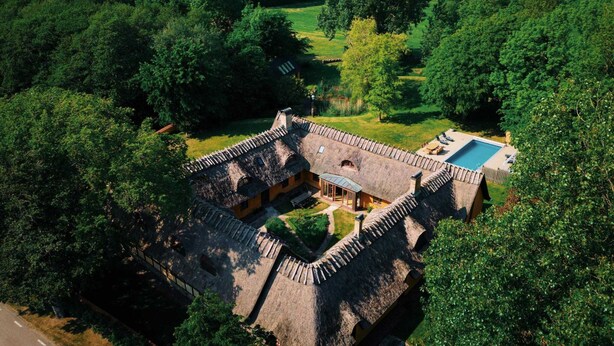 A traditional building with a thatched roof, surrounded by lush greenery and a pool. - 12 Person Holiday Home in Bastad-by Traum (Bastad)