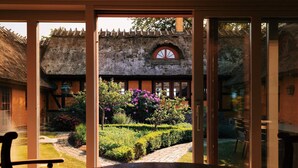 A traditional thatched-roof building with a garden view through a glass door. - 12 Person Holiday Home in Bastad-by Traum (Bastad)