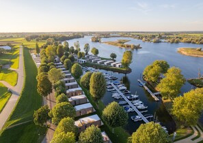 Vue aérienne d’une propriété riveraine comprenant un port de plaisance, des maisons mitoyennes et des champs verdoyants.