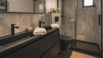 Uma casa de banho moderna com um espelho grande, duas pias, um chuveiro e uma sanita.