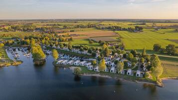 An aerial view of a lakeside campground with RVs and mobile homes, surrounded by fields and trees.