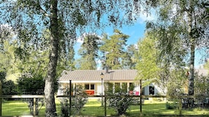 Ein Haus mit einem Ziegeldach, umgeben von einem eingezäunten Garten mit Gras und Bäumen.