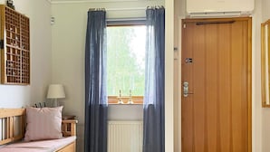 Ein gemütliches Zimmer mit einer hölzernen Bank, einem Heizkörper, einer Tür und einem Fenster mit Vorhängen.