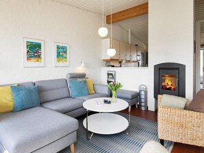 A modern living room with a grey sectional sofa, a round coffee table, a wicker armchair, and a fireplace.
