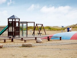 Un parque infantil con tobogán, columpios y una estructura para escalar.