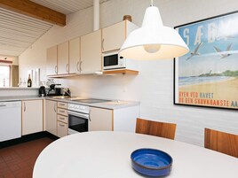 A modern kitchen with white cabinets, a microwave, and a large white pendant light.
