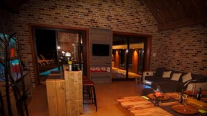A cozy living area with a wooden bar, a sofa, and a dining table set for two. - Villa With Swimming Pool in Erembodegem (Aalst)