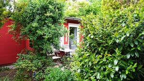 A small, red building with a white door, surrounded by lush green foliage. - Holiday Home With art (Leipzig)