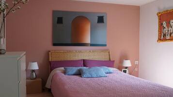 A bedroom with a bed, two bedside tables, a wall-mounted painting, and a framed picture.