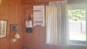 A room with wooden walls, a window with curtains, a heater, and a framed picture. - 6 Person Holiday Home in Rorvig (Rørvig)