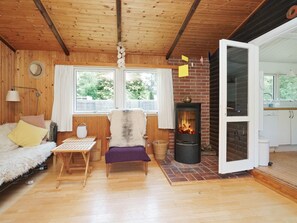 A cozy cabin interior with a fireplace, wooden walls, a sofa, and a dining table.