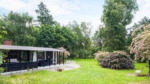 A house with a covered porch, a lawn, and surrounding trees. - 6 Person Holiday Home in Rorvig (Rørvig)