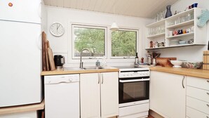 A kitchen with white cabinets, a Bosch dishwasher, a sink, a stove, and a window providing natural light. - 6 Person Holiday Home in Rorvig (Rørvig)