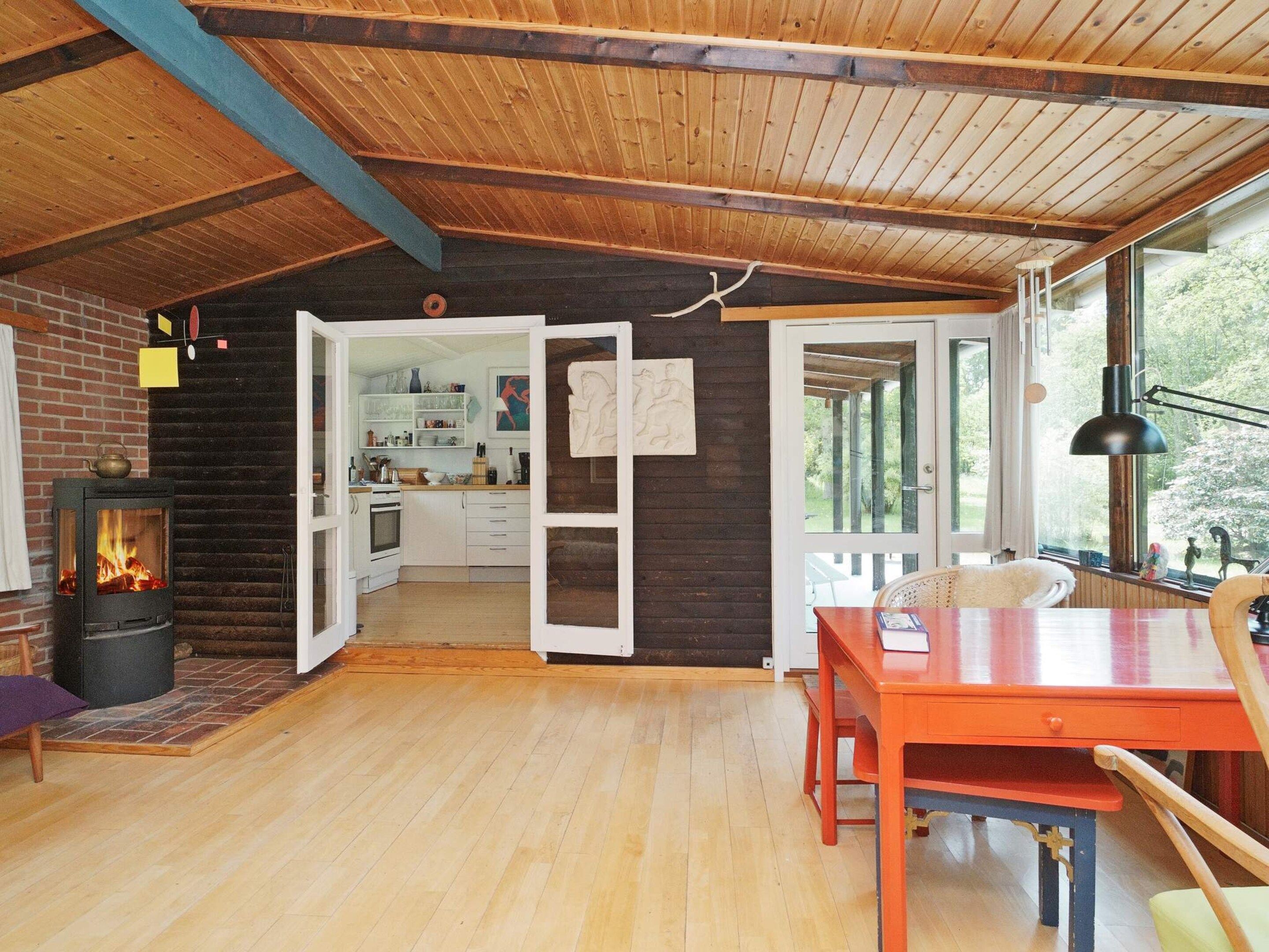 Un interior acogedor de cabaña con un estufa de leña, comedor y cocina.