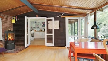 Un interior acogedor de cabaña con un estufa de leña, comedor y cocina.