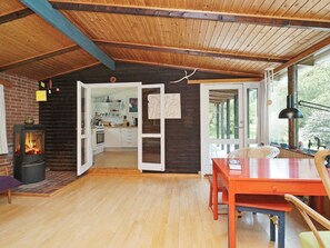 Un interior acogedor de cabaña con un estufa de leña, comedor y cocina.
