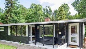 A small, single-story house with a covered porch, a sliding glass door, and a small outdoor seating area. - 6 Person Holiday Home in Rorvig (Rørvig)