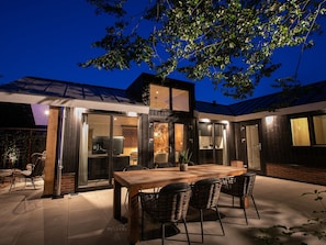 A modern house with a dining area, large windows, and a tree. - Luxury Lodge With Private Swimming Pool (Rhenen)