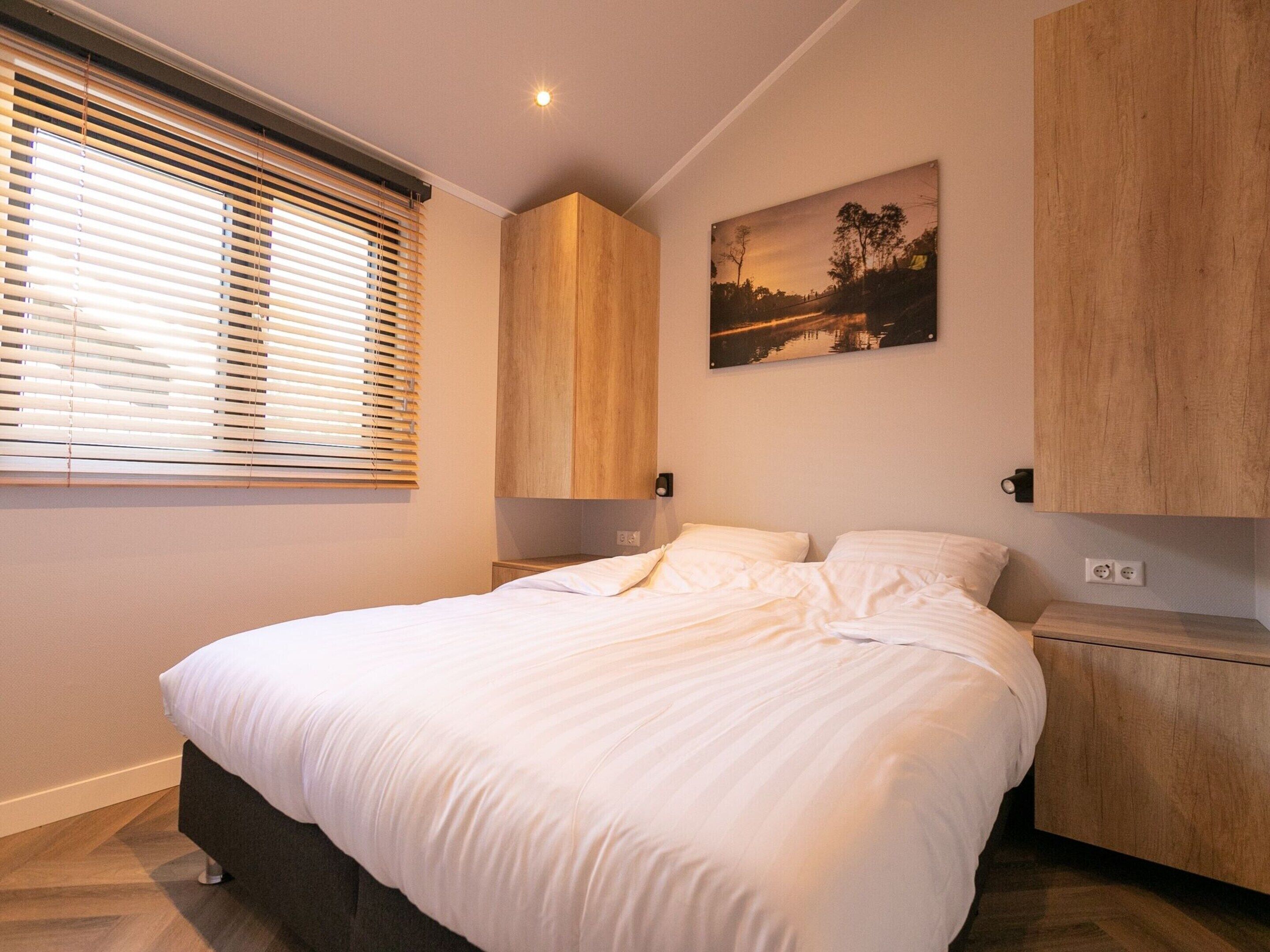 Un dormitorio con cama, cabecero de madera, mesitas de noche y un cuadro colgado en la pared.