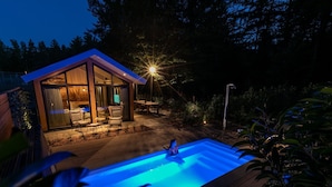 Une maison moderne dotée d’une piscine, d’un espace salon extérieur et d’une terrasse bien éclairée.
