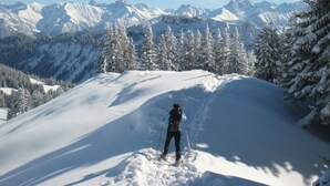 A person skiing on a snowy mountain slope with a view of snow-covered peaks and trees in the background. - Hofatsblick With Sauna (Fischen im Allgaeu)