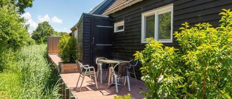 A wooden house with a patio, a table, and chairs.