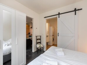 Ein Hotelzimmer mit Bett, Stuhl, Kleiderschrank und einer Schiebetür zu einem Badezimmer.