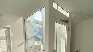 A modern interior with a glass elevator, a staircase, and a door leading to another room. - Holiday Apartment Meadow (Sulzburg)
