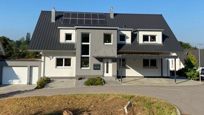 A modern two-story house with a grey roof, white walls, and a small front yard. - Holiday Apartment Meadow (Sulzburg)