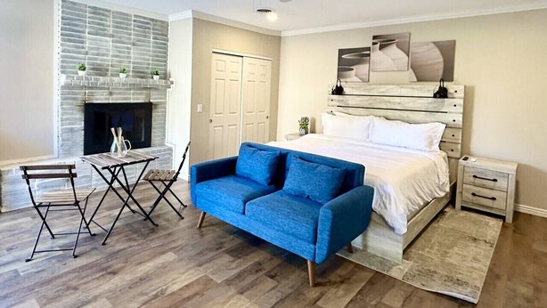 Quarto com uma cama, um sofá azul, uma mesinha e uma lareira.