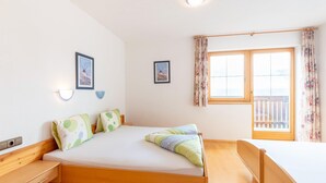 Quarto com cama, mesas de cabeceira, janela com cortinas e luminárias fixadas na parede.