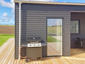 A barbecue grill on a wooden deck with a view of a grassy field. - 12 Person Holiday Home in Lemvig (Lemvig)