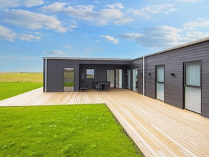 A modern house with a wooden deck, a dining area, and a large glass door. - 12 Person Holiday Home in Lemvig (Lemvig)