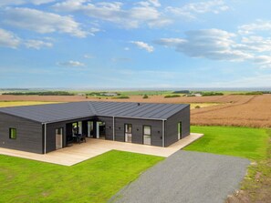 A modern house with a flat roof, a covered patio, and a view of the surrounding fields. - 12 Person Holiday Home in Lemvig (Lemvig)