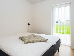 A bedroom with a bed, a power outlet, and a view of a green field through a window. - 12 Person Holiday Home in Lemvig (Lemvig)