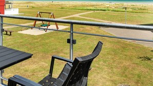 A patio with a swing set and a view of the beach. - 4 Person Holiday Home in Hadsund (Hadsund)