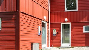 A red building with two doors, a window, and a small outdoor area with a bench. - 4 Person Holiday Home in Hadsund (Hadsund)