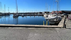 A marina with boats docked, a clear sky, and a building in the background. - 4 Person Holiday Home in Hadsund (Hadsund)