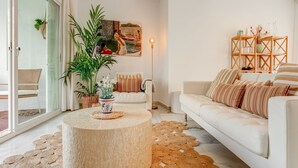 A modern living room with a round coffee table, a white sofa, and a glass door leading to a balcony.
