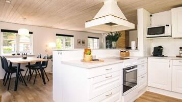 A modern kitchen with white cabinetry, a central island, a built-in oven, and a microwave.