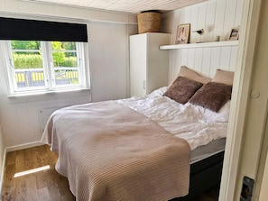 A bedroom with a bed, a window, a wardrobe, and a shelf with items. - 4 Star Holiday Home in Lokken (Lokken)