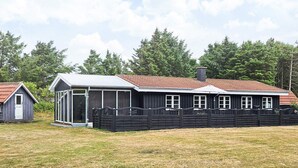 A two-story building with a red-tiled roof, a covered porch, and a fenced yard.