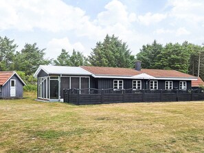 A two-story building with a red-tiled roof, a covered porch, and a fenced yard. - 4 Star Holiday Home in Lokken (Lokken)