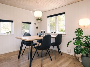 A dining area with a wooden table, black chairs, and a potted plant. - 4 Star Holiday Home in Lokken (Lokken)
